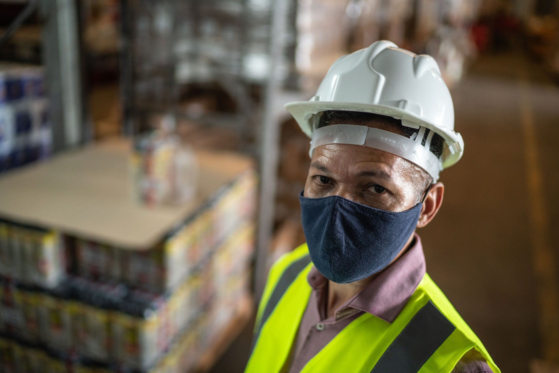 Verticale d’un homme mûr utilisant le masque facial et les vêtements de travail protecteurs dans un entrepôt